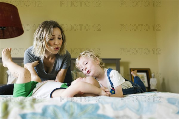 Mother playing with sons (12-17 months, 4-5) in bedroom