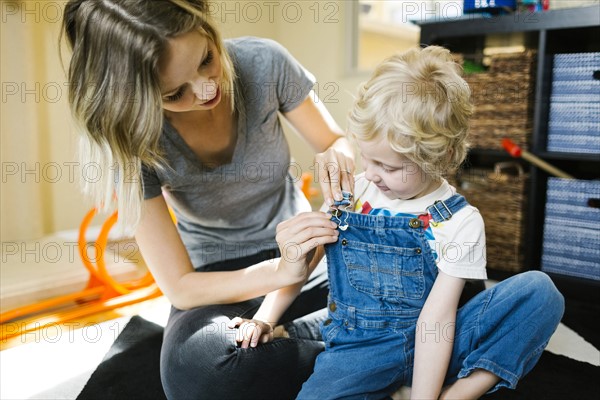 Mother dressing son (4-5)