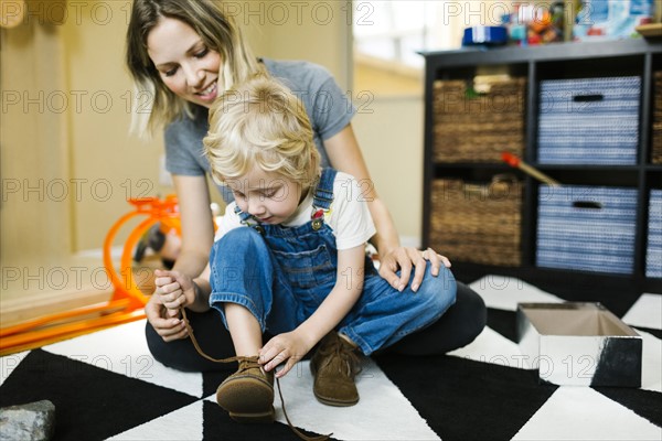 Mother learning son (4-5) to tie shoes