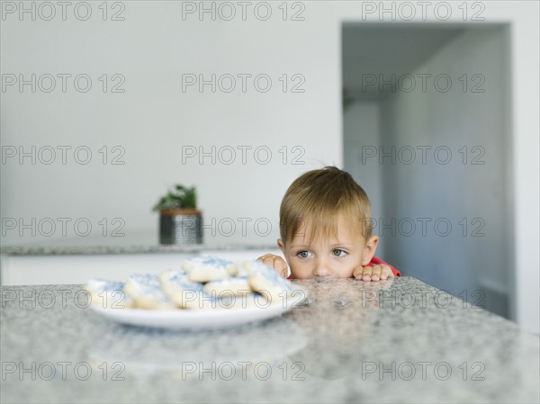 Boy (2-3) looking at cookies on kitchen counter