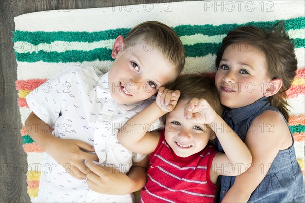 Portrait of siblings (2-3, 6-7) lying on carpet