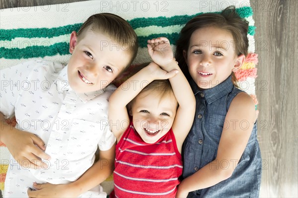 Portrait of siblings (2-3, 6-7) lying on carpet