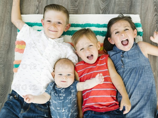 Portrait of siblings (6-11 months, 2-3, 6-7) lying on carpet