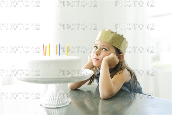 Sad girl (6-7) with birthday cake