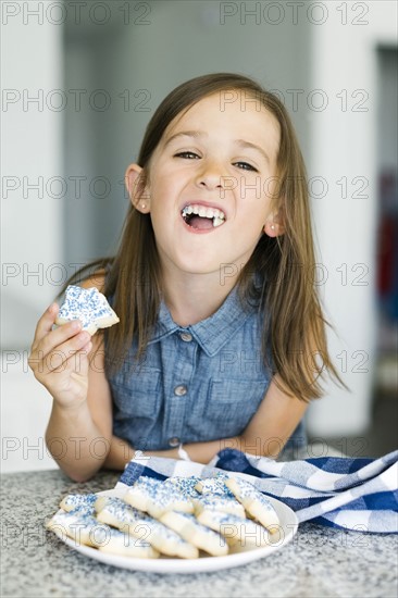 Portrait of girl (6-7) eating cookies
