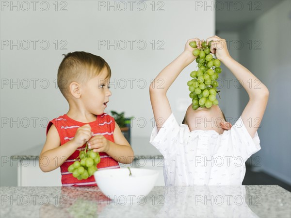 Boys (2-3, 6-7) eating white grapes