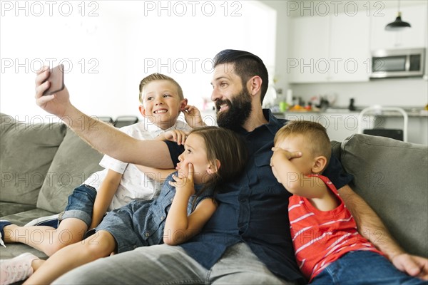 Father with his three children (2-3, 6-7) taking selfie with smart phone