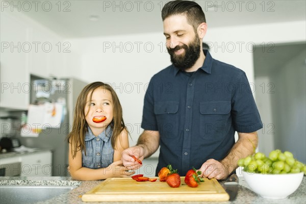 Father with daughter (6-7) eating strawberries