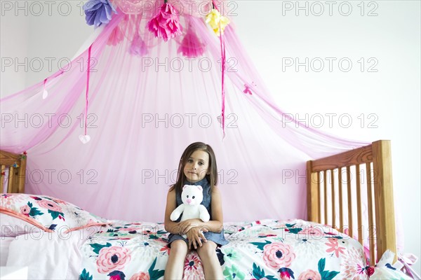 Girl (6-7) sitting on bed