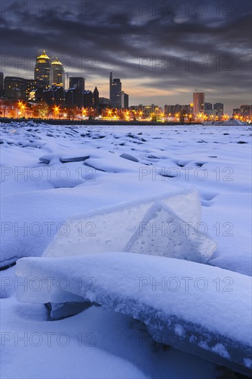 Ukraine, Dnepropetrovsk region, Dnepropetrovsk city, Frozen river with distant city skyline at dusk