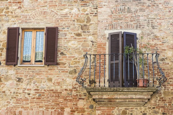 Italy, Tuscany, Montepulciano, Stony and brick facade of house with carved metal balcony and latticed sun blinds