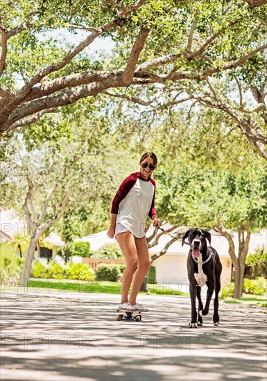 Woman on skate board with Great Dane