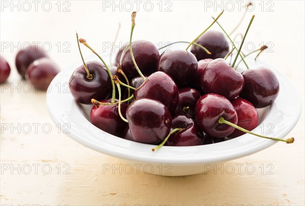 Ripe cherries in white bowl on table