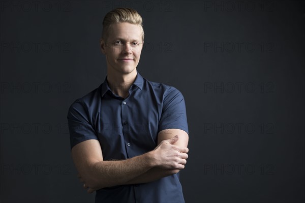 Portrait of man with crossed arms on black background