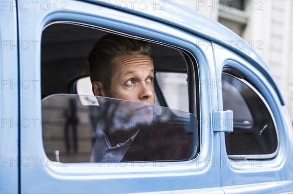 Man looking through window in retro car