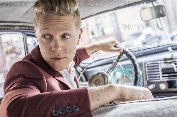 Man driving vintage car, looking over shoulder