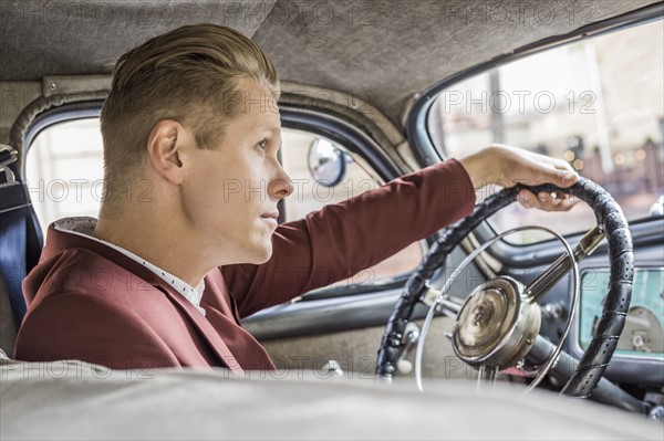 Blond man driving vintage car