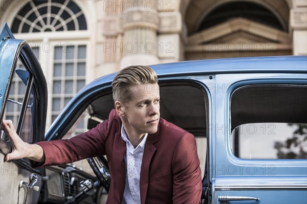 Handsome man disembarking vintage car