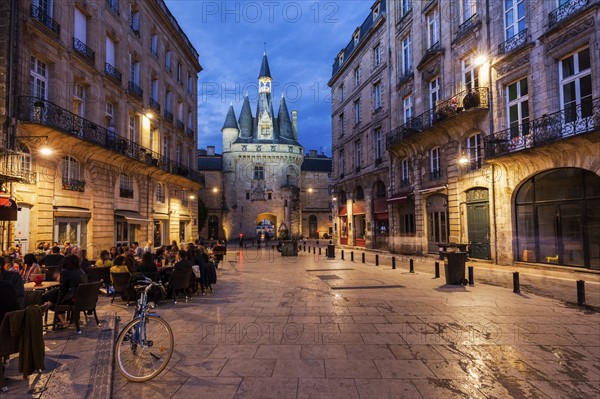 France, Nouvelle-Aquitaine, Bordeaux, Crowded sidewalk cafe with Cailhau Gate in background