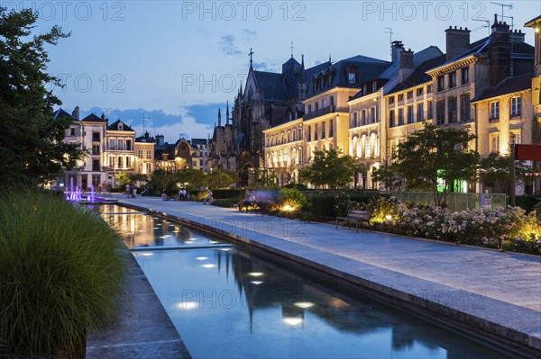 France, Grand Est, Troyes, Promenade along canal with illuminated buildings in background