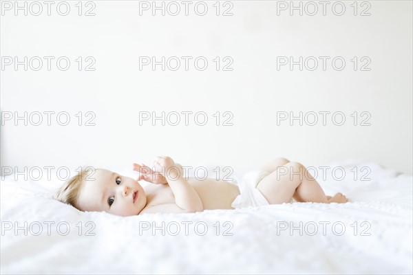 Portrait of baby girl (6-11 Months) lying down on bed