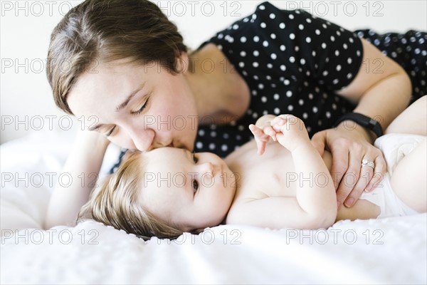 Baby girl (6-11 Months) being kissed by mother