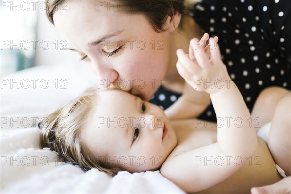 Baby girl (6-11 Months) being kissed by mother