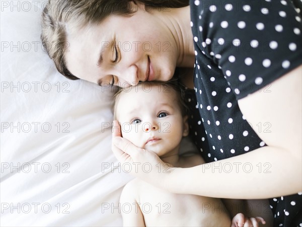 Baby girl (6-11 Months) being hugged by mother, directly above