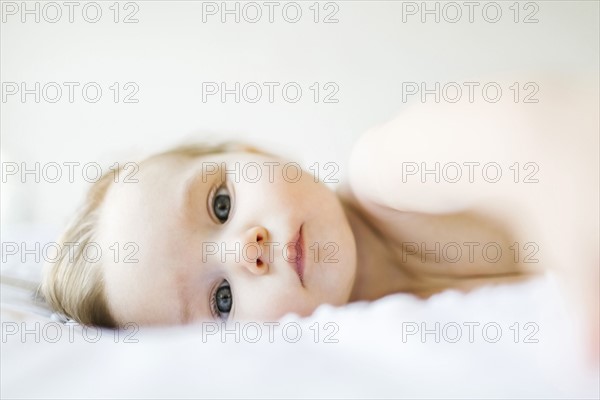 Portrait of baby girl (6-11 months) lying on bed