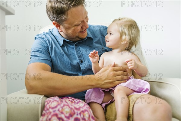 Father with baby girl (12-17 months) sitting in living room