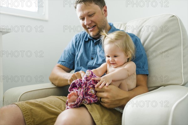 Father with baby girl (12-17 months) sitting in living room