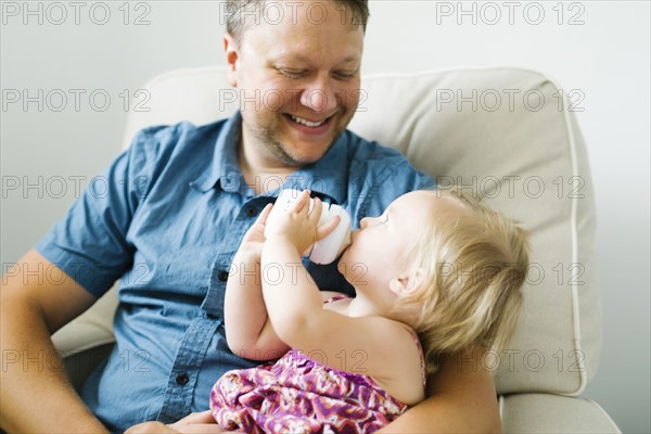 Father feeding baby girl (12-17 months) in living room