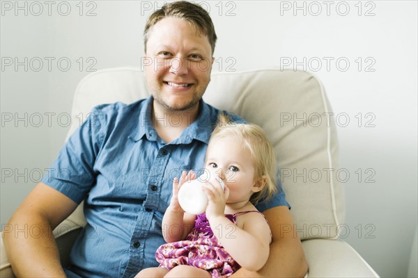 Father feeding baby girl (12-17 months) in living room