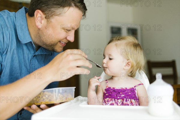 Father feeding baby girl (12-17 months)