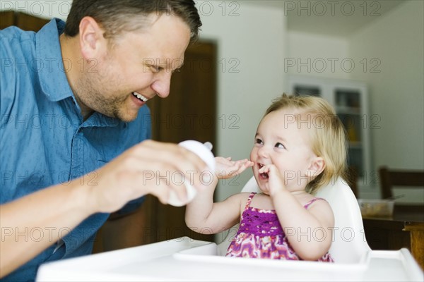 Father feeding baby girl (12-17 months)