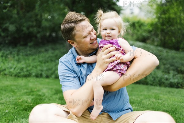 Father playing with baby girl (12-17 months) in backyard