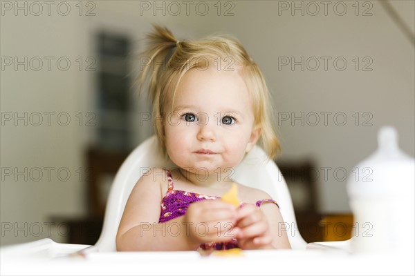 Portrait of baby girl (12-17 months) eating lunch