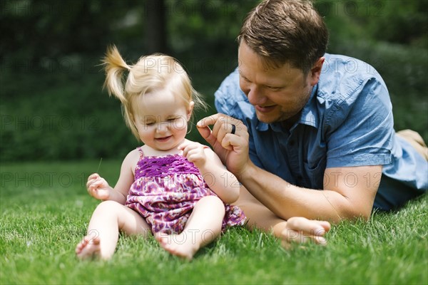 Father playing with baby girl (12-17 months) in backyard