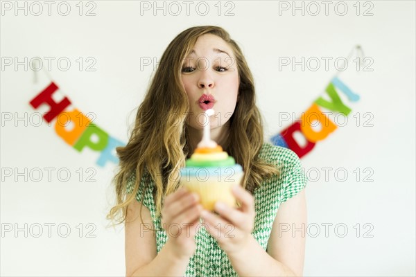 Mid adult woman blowing birthday candle