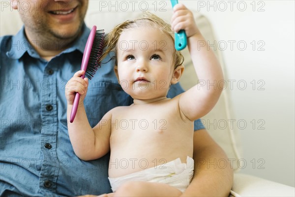 Father and baby girl (12-17 months) brushing hair after bath