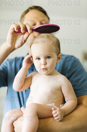 Father and baby girl (12-17 months) brushing hair after bath