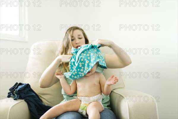 Mother getting dressed daughter (11-17 months) in living room
