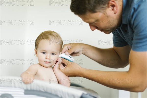 Father measuring temperature to baby girl (12-17 months)