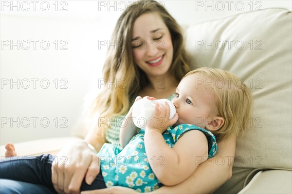 Mother feeding baby girl (12-17 months) in living room