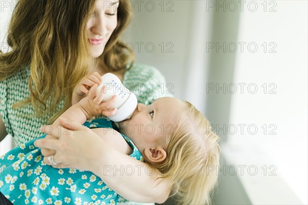 Mother feeding baby girl (12-17 months) in living room