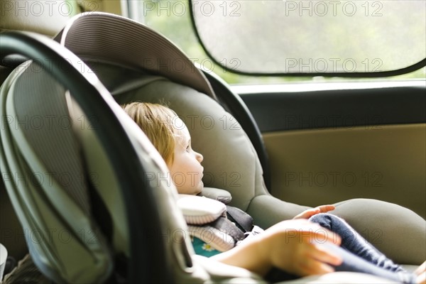 Baby girl (12-17 months) sitting in baby car seat during car trip