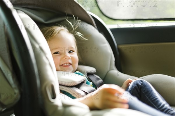 Baby girl (12-17 months) sitting in baby car seat during car trip