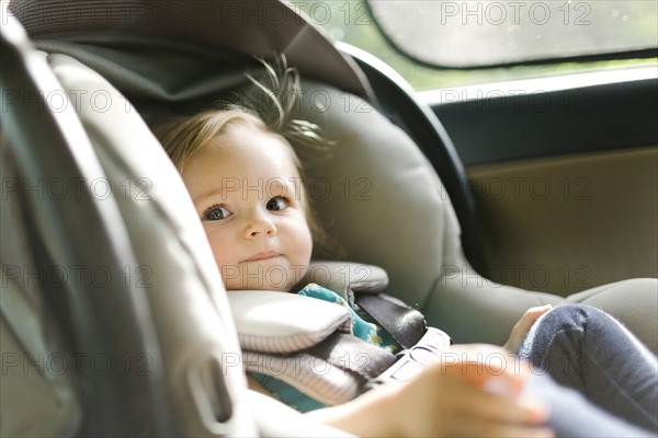 Baby girl (12-17 months) sitting in baby car seat during car trip