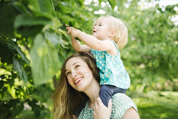 Mother carrying daughter (12-17 months) on shoulders