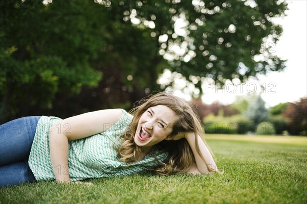 Portrait of woman lying on grass and laughing